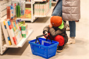 Family is shopping at the store. Little boy choosing some toy in supermarket. Boy holding shopping basket. Sales, shopping and people concept.